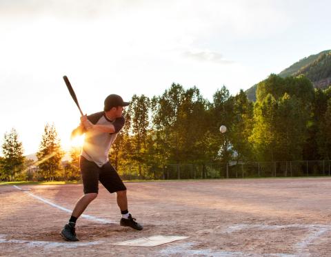 Stock image of a man about to hit a softball with a bat.