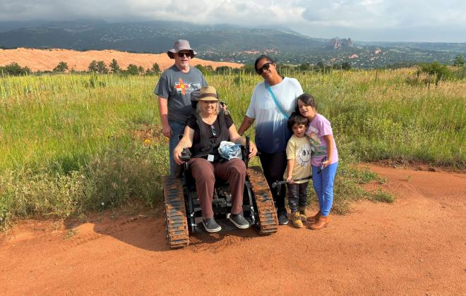 A track chair user with their family in Red Rock Canyon.
