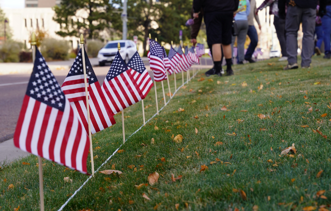 Small flags line a section of grass next to a sidewalk in Downtown Colorado Springs.